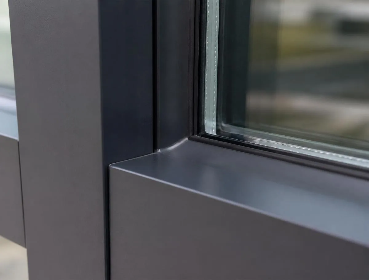 Close-up of a tooled silicone sealant joint between a dark anodized aluminum curtain wall mullion and insulated glass